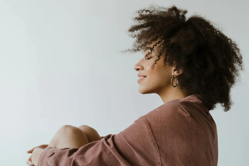 silver twisted hoop earrings with polished finish worn by woman with curly hair in casual brown top