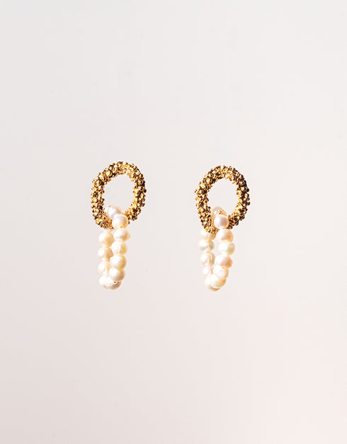 Pair of gold hoop earrings with pearl-like beads on a light background