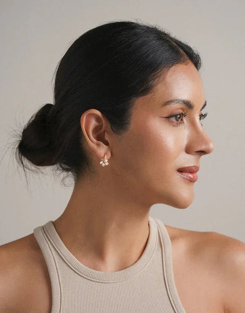 Gold pierced stud earrings with cluster of small clear gemstones, elegant minimalist style