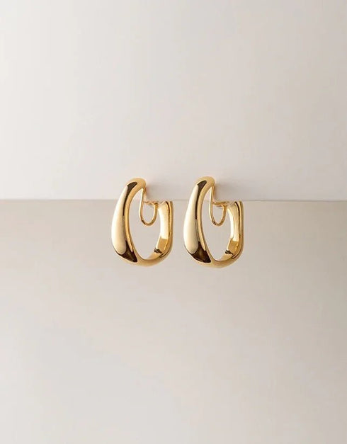 Gold polished hoop earrings with thick, curved design, modern minimalist style jewelry